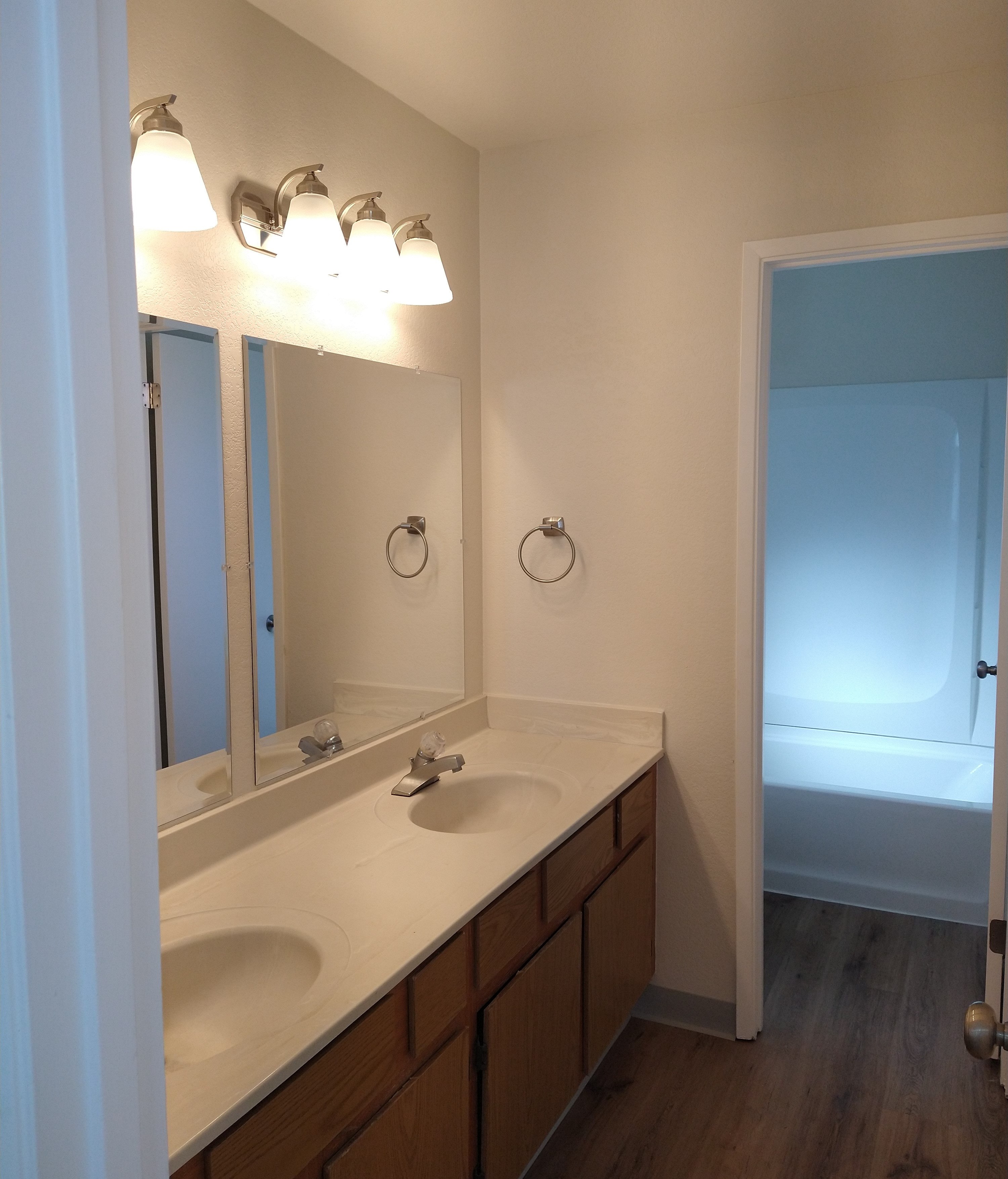 A bathroom with a sink, mirror and lighting.